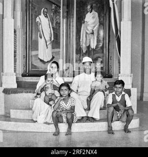 Vecchia foto vintage in bianco e nero degli anni '1900 di famiglia indiana marito moglie figli sotto Kasturba Mahatma Gandhi ritratto Rajkot Gujarat India anni '1950 Foto Stock