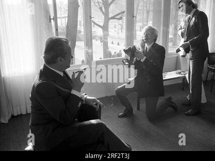 FOTO DI ARCHIVIO: Andy WARHOL avrebbe avuto 95 anni il 6 agosto 2023, ARTE/politica Andy WARHOL(r.), USA, artista, Ritrarre l'ex cancelliere Willy BRANDT (SPD) con una fotocamera istantanea. Warhol si sta inginocchiando su una gamba, tenendo la fotocamera in alto, ma non la guarda attraverso, sembra invece dare istruzioni a Brandt. Brandt siede su una sedia e tiene una sigaretta con un boccaglio nella mano destra, a metà lunghezza nel profilo e piuttosto simile a una silhouette, ma ancora riconoscibile. Warhol può essere visto in una figura intera dal fronte. Foto in bianco e nero, formato paesaggio, 19 febbraio 1976 Foto Stock