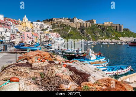Reti da pesca e variopinte barche da pesca ormeggiate al porto di Corricella a Procida, Campania, Italia Foto Stock