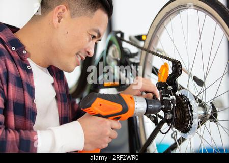 meccanico di biciclette che lavora su ruote con avvitatore a batteria Foto Stock