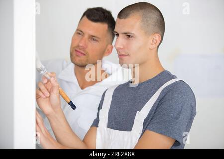 apprendista maschile dipingendo un soffitto Foto Stock