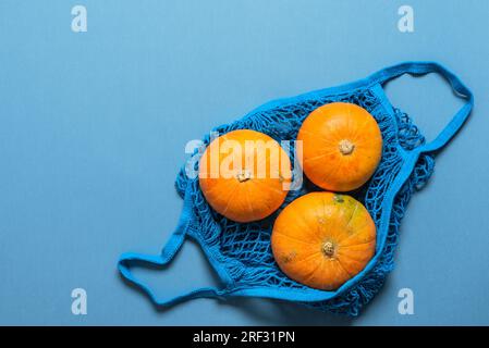 Zucche gialle in un sacchetto di cotone con cordoncino su sfondo blu. Vista dall'alto, orizzontale, spazio di copia. Il Ringraziamento e il concetto di halloween. Foto Stock