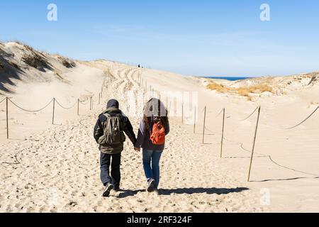 Un paio di viaggiatori con zaino in spalla passeggiano lungo le dune di sabbia collinari sulla Curonian Spit, Lituania. Foto Stock