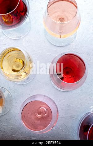 Bicchieri di vino ad una degustazione. Vino rosa, rosso e bianco, bevande su un tavolo in un'azienda vinicola, scattate dall'alto. Un assortimento di vini di molti colori diversi Foto Stock