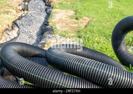 Tubo di scarico nero per acque piovane utilizzato per mitigare le acque sotterranee. Forma arrotondata astratta. Foto Stock