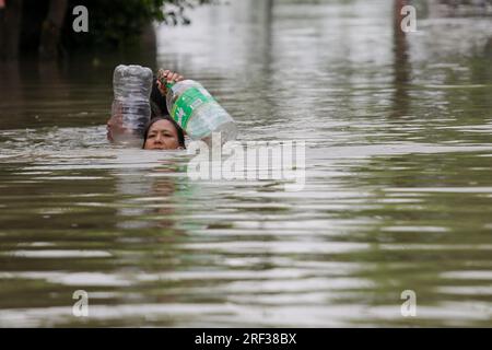 Calumpit, Bulacan, Filippine. 31 luglio 2023. I residenti usano contenitori di plastica come galleggianti mentre attraversano una strada allagata a Calumpit City, nella provincia di Bulacan a nord di Manila, nelle Filippine. Le piogge monsoniche continuano anche quando il tifone Doksuri ha lasciato il paese, lasciando inondate molte parti di Manila e delle province vicine. (Immagine di credito: © Basilio Sepe/ZUMA Press Wire) SOLO USO EDITORIALE! Non per USO commerciale! Foto Stock