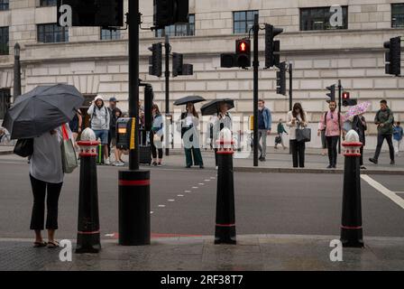 Londra, Regno Unito: Persone in attesa di attraversare la strada in un passaggio pedonale sotto la pioggia. Victoria Embankment vicino alla stazione di Blackfriars nella City di Londra. Foto Stock