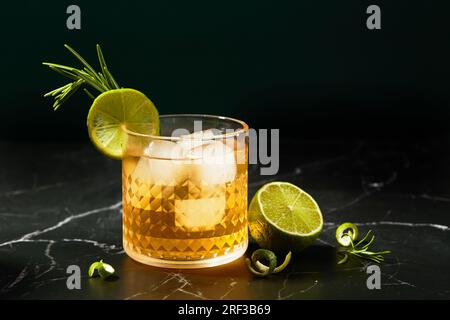 Cocktail alcolico o analcolico con lime e rosmarino su un tavolo in marmo scuro. Foto Stock