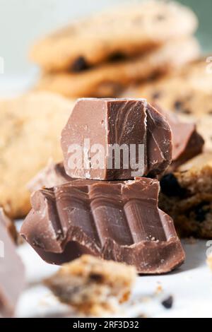 grandi pezzetti di cioccolato dolce insieme a biscotti con pezzi di cioccolato all'interno come ripieno, biscotti con gocce di cioccolato da vicino, biscotti con farina di grano Foto Stock