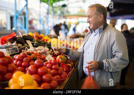 Uomo che acquista peperoni in gregrocery Foto Stock