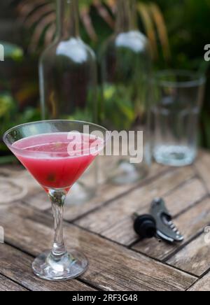 Cocktail rosso con ghiaccio in vetro con stelo su superficie di legno Foto Stock