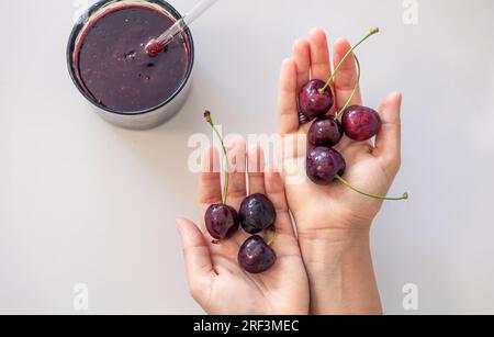 Frullati e ciliegie mature in mani femminili. Foto Stock