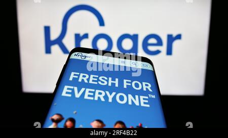 Smartphone con pagina Web del settore retail statunitense The Kroger Company sullo schermo davanti al logo. Mettere a fuoco in alto a sinistra sul display del telefono. Foto Stock