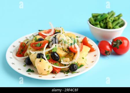 Piatto di gustosa insalata di patate con verdure su sfondo blu Foto Stock