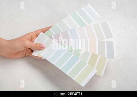 Mano con tavolozze di colori su sfondo chiaro Foto Stock