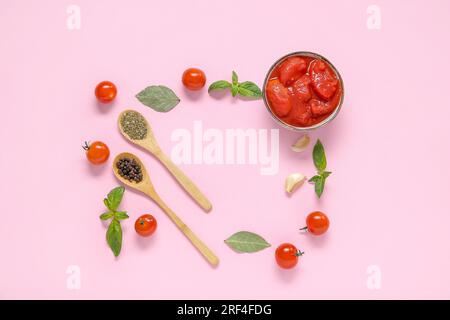 Cornice composta da pomodori in scatola e spezie su sfondo rosa Foto Stock