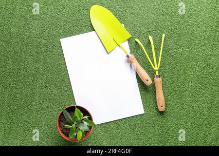 Composizione con foglio di carta bianco, strumenti per il giardinaggio e impianto in vaso su sfondo colorato Foto Stock