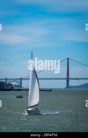 Foto verticale di una barca che naviga con il Golden Gate Bridge sullo sfondo a San Francisco, California, USA Foto Stock