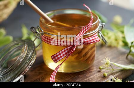 Un vaso di vetro di miele con fiori di lino freschi Foto Stock