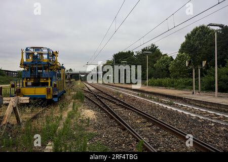 Binari ferroviari e un veicolo di servizio su un binario visto dal suo bordo in una giornata nuvolosa nella campagna italiana Foto Stock