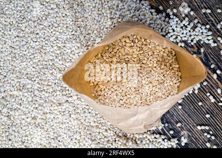 grano grezzo solido di orzo perlato, grano essiccato per la produzione e la cottura di porridge a buon mercato, orzo perlato sulla tavola da cucina closeup Foto Stock