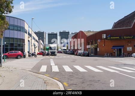 Barcellona, Spagna, 8 maggio 2023: Incrocio nella zona industriale della città vicino a magazzini, camion parcheggiati, auto in movimento lungo la strada Foto Stock