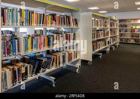 Interno della biblioteca locale della città di Farnborough con libri disponibili per il prestito sugli scaffali, Hampshire, Inghilterra, Regno Unito Foto Stock