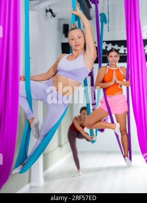 Yoga aereo in amaca. Donna snella esegue lo yoga a volo di gravità e gli esercizi di stretching Foto Stock