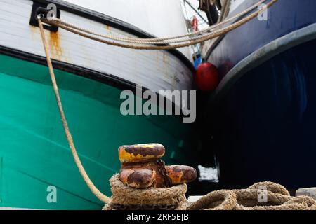 Barche da pesca legate a Rusty Harbor Bollard Foto Stock
