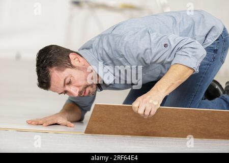 Uomo di installare nuovi in legno laminato piano in prossimità fino Foto Stock