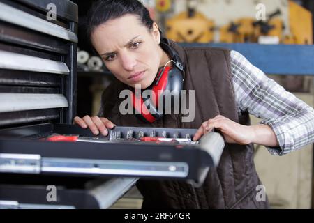 lavoratrice di fabbrica che lavora con una scatola metallica in una fabbrica Foto Stock