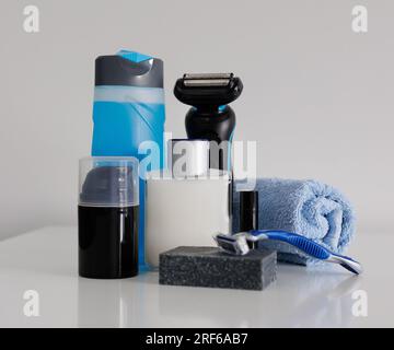 Bottiglie di prodotti cosmetici e rasoi da uomo su sfondo chiaro Foto Stock