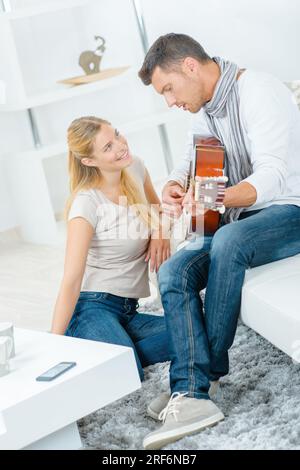 Uomo a suonare la chitarra per signora Foto Stock