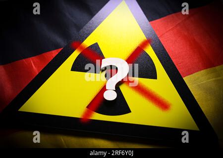 FOTOMONTAGE, Schild mit durchgestrichenem Radioaktivitätssymbol und Fragezeichen auf Deutschlandfahne, Symbolfoto für AKW-Abschaltung und Energieverso Foto Stock