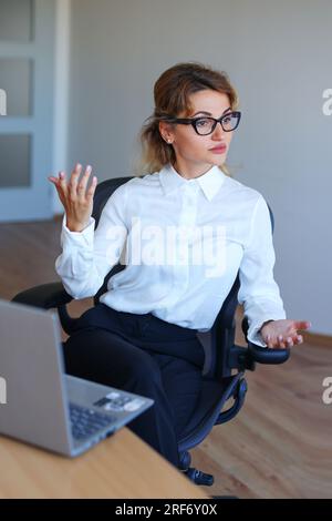 Donna d'affari che conduce una conferenza. Professionista che presenta un'idea ai suoi colleghi. Discussione di gruppo in un ufficio moderno. Foto Stock