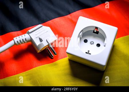 Von Steckdose getrennter Stecker auf Deutschlandfahne, Symbolfoto für AKW-Abschaltung Foto Stock