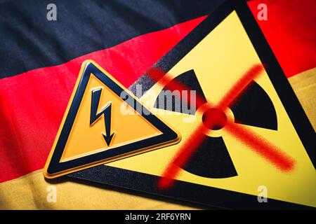 FOTOMONTAGE, Schild mit durchgestrichenem Radioaktivitätssymbol und Schild mit Strompfeil auf Deutschlandfahne, Symbolfoto für die AKW-Abschaltung Foto Stock
