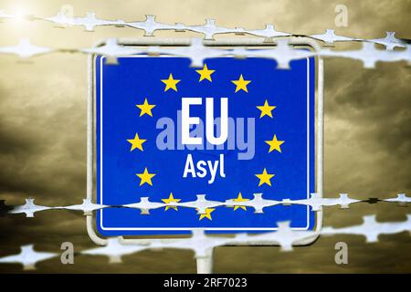 FOTOMONTAGE, EU-Schild mit Aufschrift Asyl und Stacheldraht Foto Stock