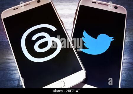 FOTOMONTAGE, Auf einem Tisch smartphone liegen mit den Logos von Threads und Twitter, neuer Kurznachrichtendienst Threads Will Twitter Konkurrenz mac Foto Stock