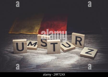 Buchstaben bilden den Schriftzug Umsturz vor einer Deutschlandfahne Foto Stock