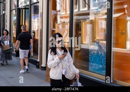 Scena di strada mentre gli acquirenti e i visitatori passano in Bond Street nell'area esclusiva di Mayfair il 7 luglio 2023 a Londra, Regno Unito. Bond Street è una delle strade principali del quartiere dello shopping del West End ed è molto esclusiva. E' stata una strada alla moda per lo shopping fin dal XVIII secolo. Il ricco e ricco negozio qui, soprattutto di alta moda e gioielleria. Foto Stock
