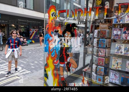 In un angolo di Berwick Street a Soho, alla fine del mercato, la vetrina della graphic novel e del fumetto Gosh Comics interagisce con i passanti in una colorata scena di strada il 9 luglio 2023 a Londra, Regno Unito. Foto Stock