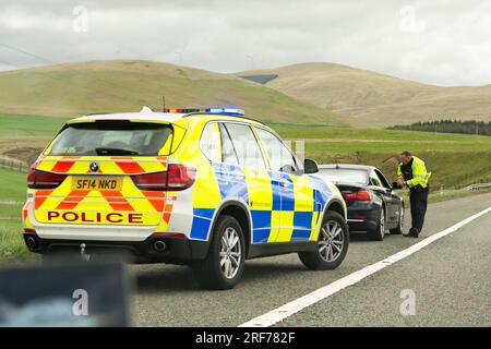 Agente della polizia stradale che parla al conducente di una bmw nera che è stata fatta per accostare sulla spalla rigida dell'autostrada M74 Scozia, Regno Unito Foto Stock