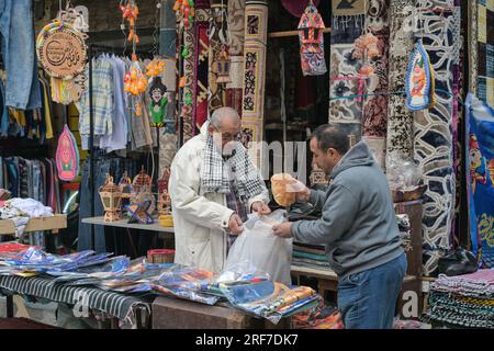 Straßenszene, Textilgeschäft, Teppiche, Männer, Brot, Khan el-Khalili Basar, Altstadt, Kairo, Ägypten Foto Stock