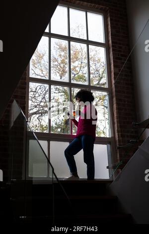 Donna birazziale che beve tè e usa lo smartphone a casa, spazio per le copie Foto Stock