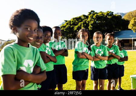 Ritratto di bambini felici e diversi che raccolgono riciclano sorridendo nel soleggiato campo della scuola elementare Foto Stock