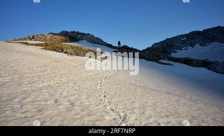 Escursionista che attraversa il campo di neve nelle alpi bavaresi si avvicina a Hundstodgatterl nel parco nazionale di Berchtesgaden, Baviera, Germania Foto Stock