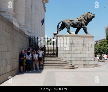 Persone in piedi all'ombra accanto al tribunale di Sofia (Sadebna Palata, o Palazzo di giustizia) nella città di Sofia, Bulgaria. 1° agosto 2023. Foto Stock