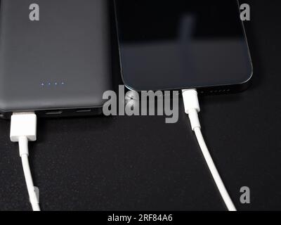 Power Bank per ricaricare i dispositivi mobili su sfondo nero. Caricabatterie per smartphone con alimentatore. Batteria esterna per dispositivi mobili. Foto Stock