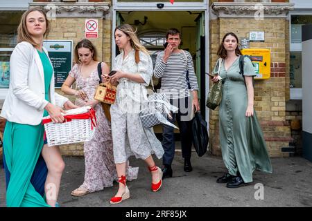 I giovani appassionati di Opera arrivano alla stazione ferroviaria di Lewes da Londra lungo il tragitto per la Glyndebourne Opera House, Lewes, East Sussex, Regno Unito. Foto Stock